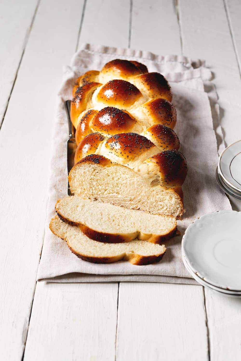 En un paño de cocina blanca está puesto el pan judío cortado en rodajas. Se ve el pan esponjoso.