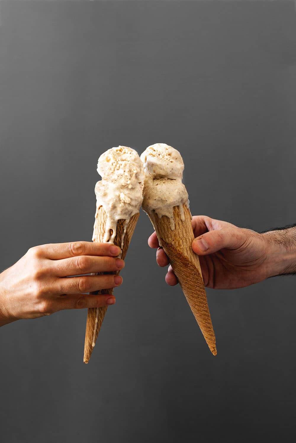 Dos manos brindan con cucuruchos llenos de helado de avena.