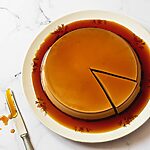En una mesa de mármol hay un plato blanco. En el plato está el flan de café con gelatina. Está cortada. Alrededor hay una salsa de caramelo deliciosa. Al lado del plato hay un cuchillo con salsa de caramelo.