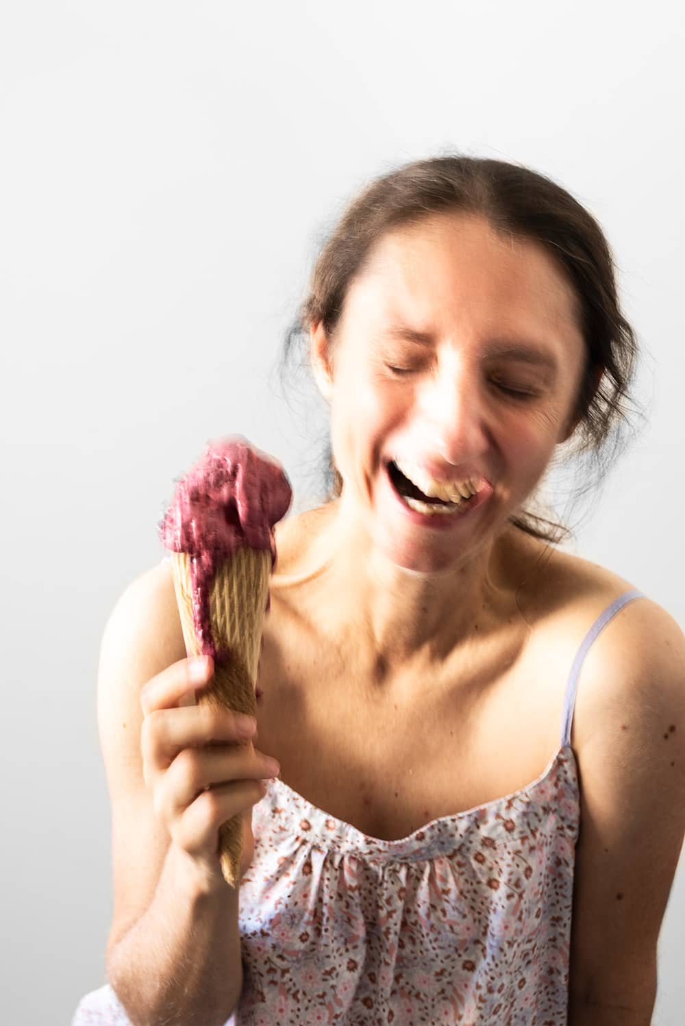 Una persona está sujetando un helado casero de mora en su mano. Se ve muy feliz porque el helado está delicioso y cremoso.