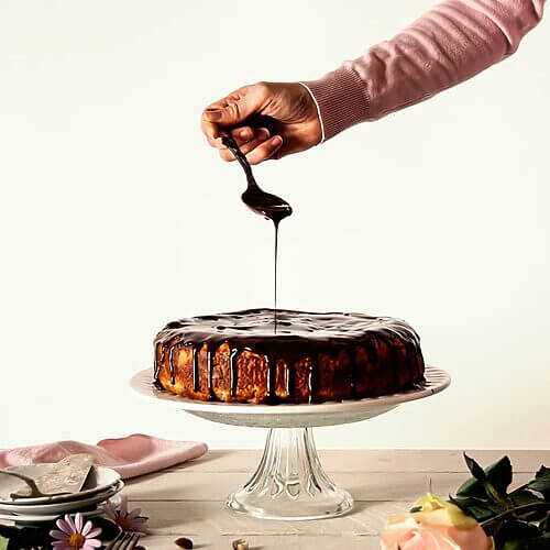 Una persona está cubriendo una tarta con ganache de chocolate con agua fácil.