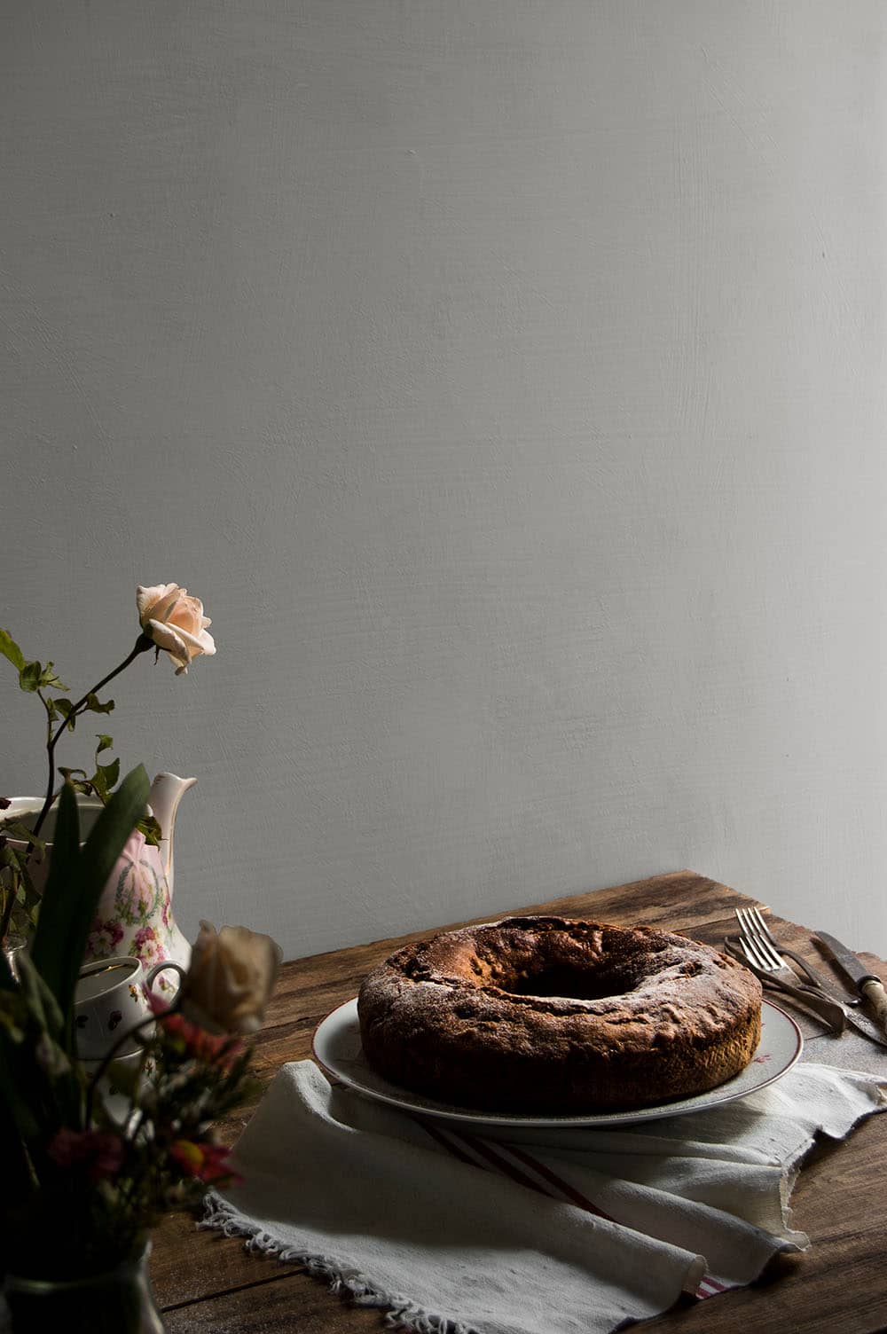 En una mesa de madera hay un plato con Plum cake de pasas ingles. 