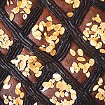 Se ve muy cerca la coca de San Juan. Se ven las almendras fileteadas tostadas, y la tiras de crema pastelera de chocolate.