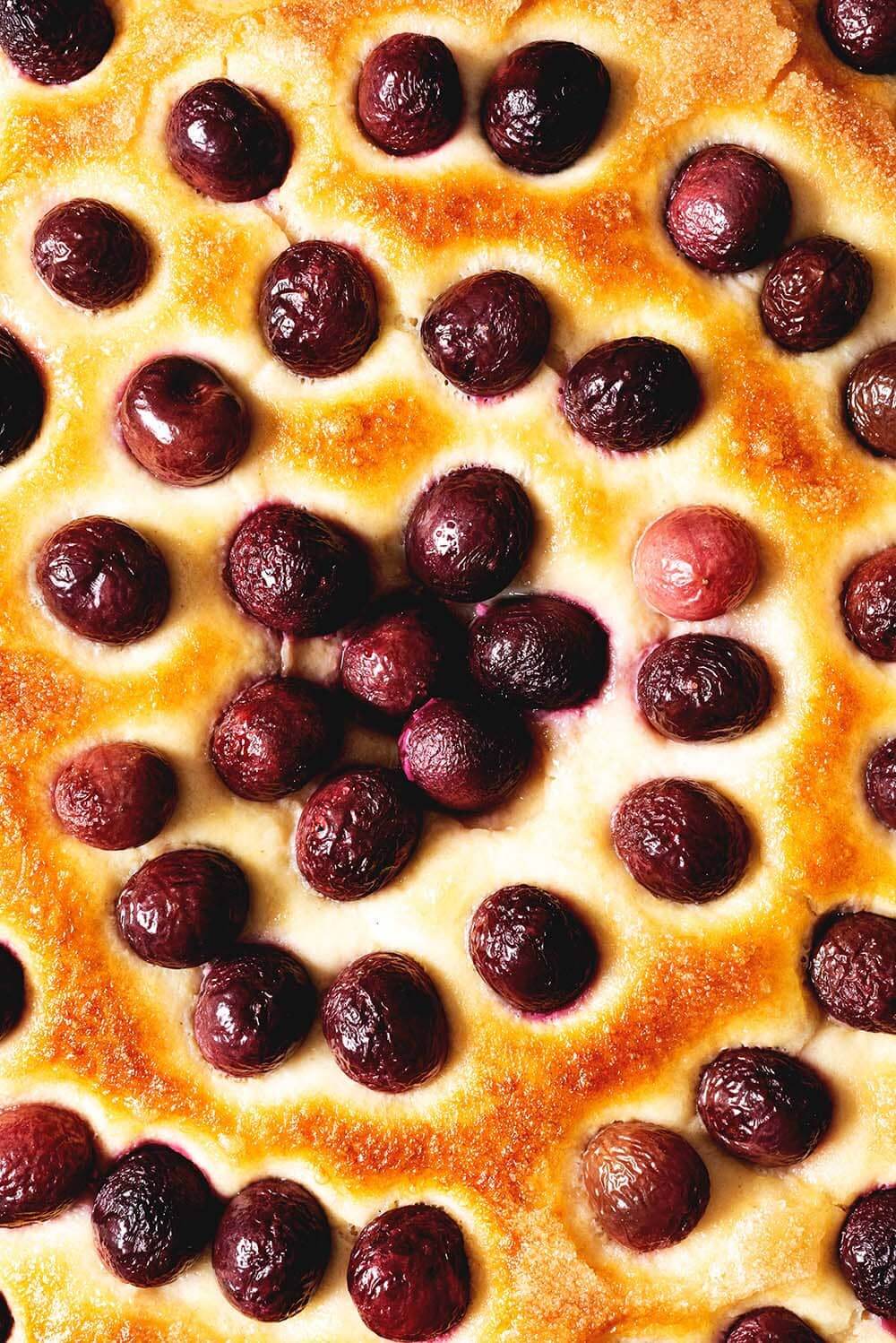 Coca de cerezas facilísimo Se ve la superficie tostada de la coca de recetas. También se ven las cerezas horneadas.