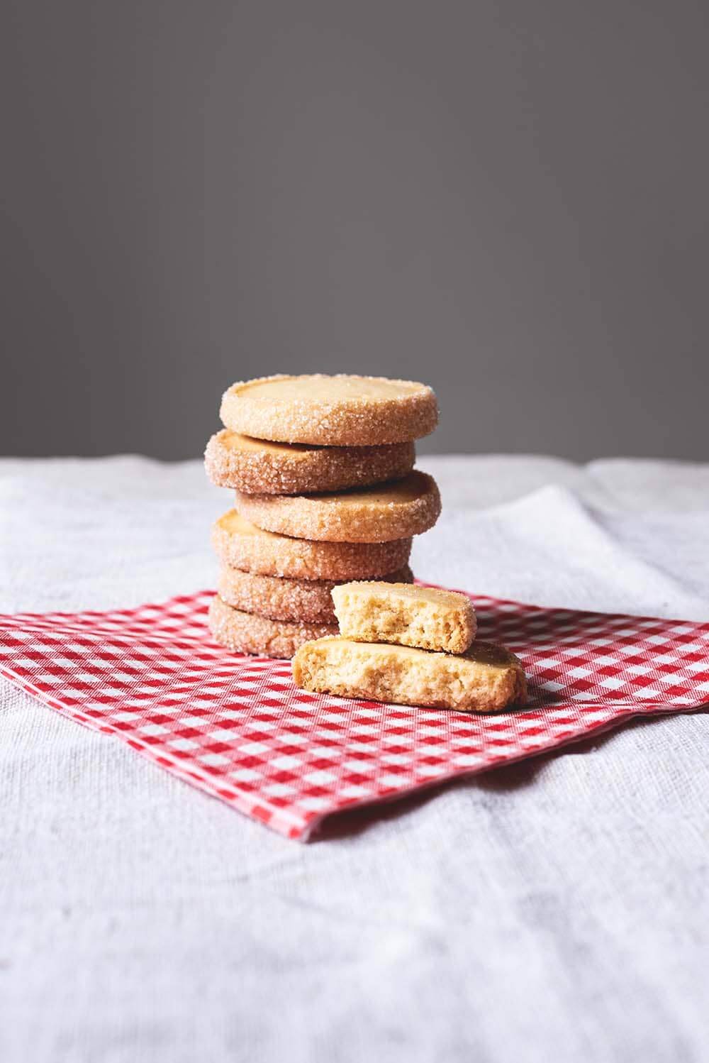 En una mesa hay un mantel blanco. Encima hay una servilleta de papel cuadros vichy rojo y blanco. Encima hay una torre de Galletas Diamante.