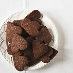 En una mesa hay un mantel blanco vintage. Encima hay un plato blanco lleno de Basler Brunsli.