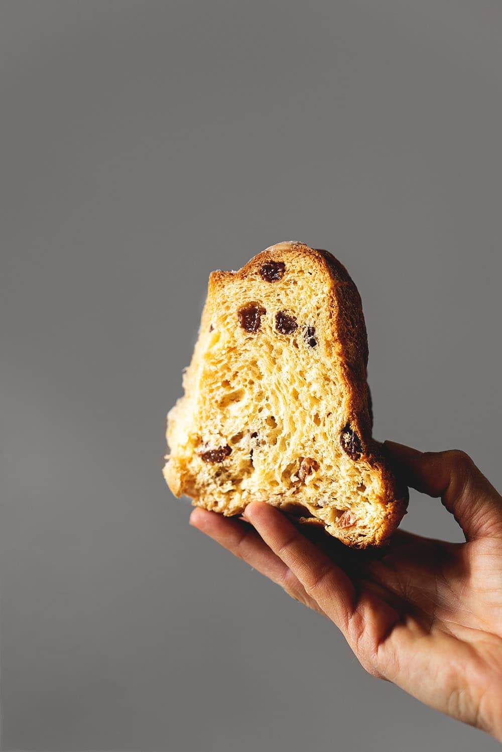 Kouglof de Alsacia Una mano está sujetando un trozo de Kouglof. Se ve muy esponjoso y tierno.