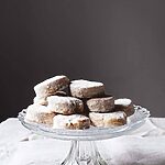 En una mesa hay un mantel blanco. Encima hay un porta tartas de cristal. Encima están muchos Nevaditos de la abuela.