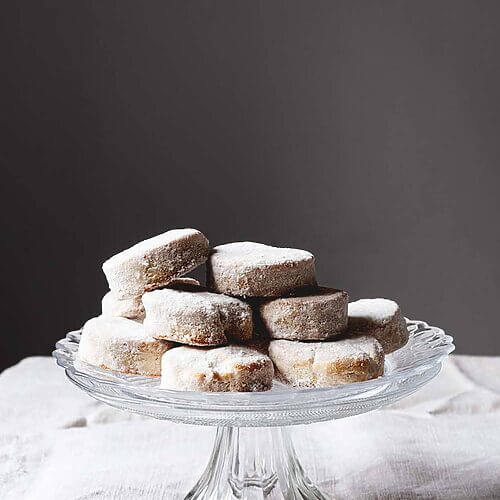 En una mesa hay un mantel blanco. Encima hay un porta tartas de cristal. Encima están muchos Nevaditos de la abuela.