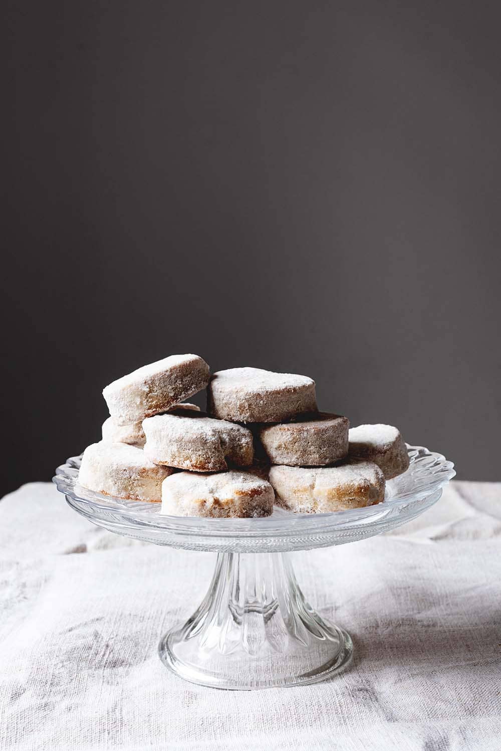 Nevaditos tradicionales En una mesa hay un mantel blanco. Encima hay un porta tartas de cristal. Encima están muchos Nevaditos de la abuela.