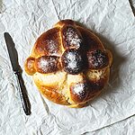 En una servita hay un pan de muerto. Al lado hay un cuchillo.