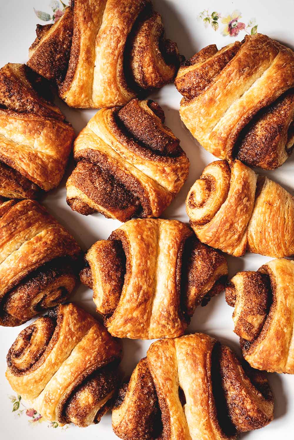 En un plato hay muchos Franzbrötchen. Se ven bien desde cerca. Están doradas y se ven deliciosos.