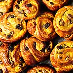 En un papel de cocina hay muchos Pains aux Raisins. Se ven doraditos jugosos y llenos de crema. Son muy apetecibles.