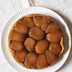 Tarta Tatin de manzana original y casera, con manzanas caramelizadas doradas y masa crujiente. Postre francés tradicional servido sobre plato blanco. Receta dulce y aromática ideal para disfrutar en cualquier ocasión.