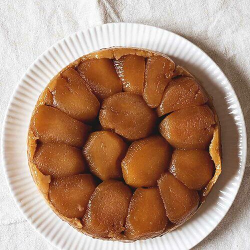 Tarta Tatin de manzana original y casera, con manzanas caramelizadas doradas y masa crujiente. Postre francés tradicional servido sobre plato blanco. Receta dulce y aromática ideal para disfrutar en cualquier ocasión.