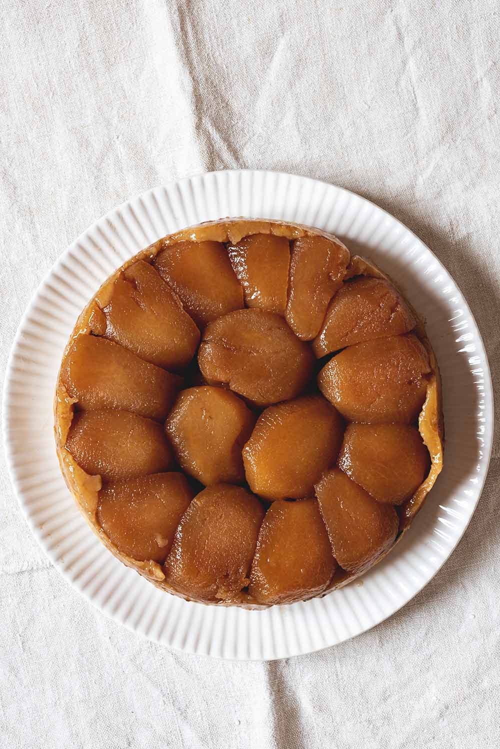 Tarta Tatin de manzana original y casera, con manzanas caramelizadas doradas y masa crujiente. Postre francés tradicional servido sobre plato blanco. Receta dulce y aromática ideal para disfrutar en cualquier ocasión.