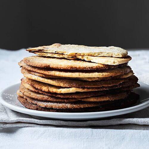 En una mesa hay un mantel blanco. Encima hay varias tortas de aceite y anís puestas encima una y otra. La última está corta. Se ve tu textura crujiente.