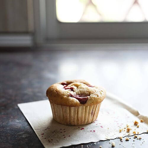 En una encimera gris hay una servilleta blanca. Encima hay una magdalena de fresas y yogur. Se ve muy delicioso.