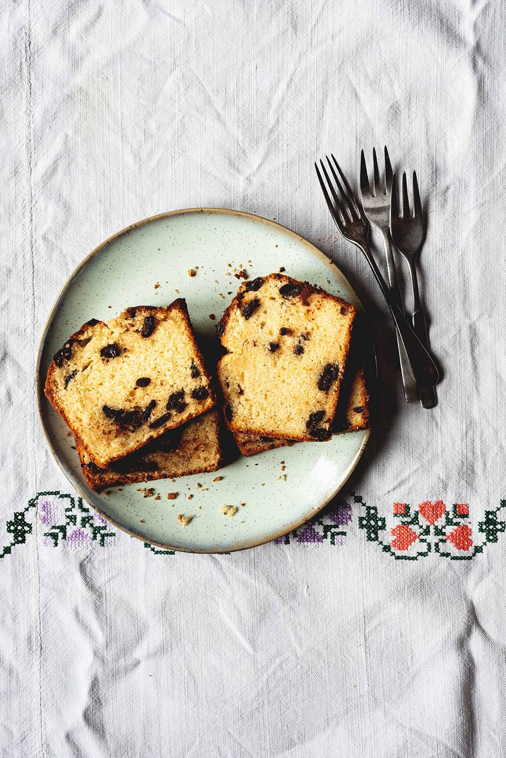 Rebanadas de bizcocho con pepitas de chocolate servidas sobre un plato de color verde claro.